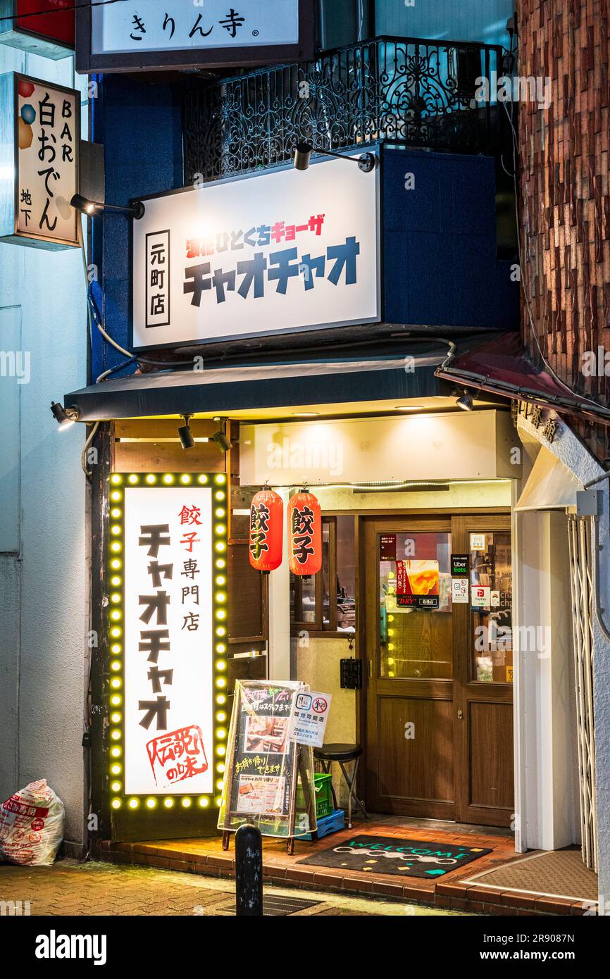Fassade und Eingang einer typisch kleinen japanischen Restaurant Bar mit "Willkommensmatte" und zwei roten Laternen, die über der Tür hängen. Es Ist Nacht. Stockfoto