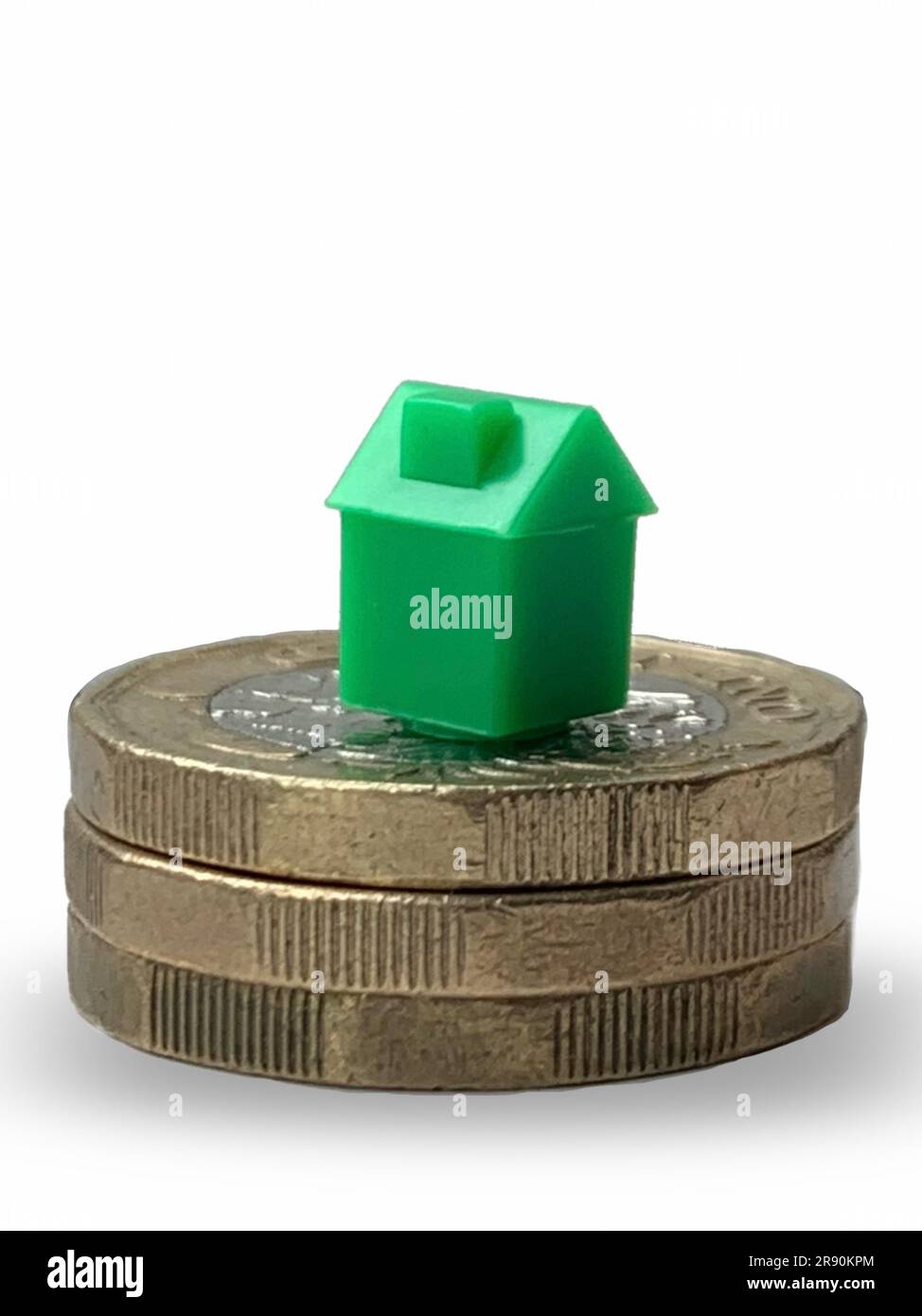 Plastikhaus auf Geldmünzen, um die Hypothekenpreise zu repräsentieren, die sinken, wenn die Inflation sinkt und die Bank of England möglicherweise die Zinsen ändert Stockfoto