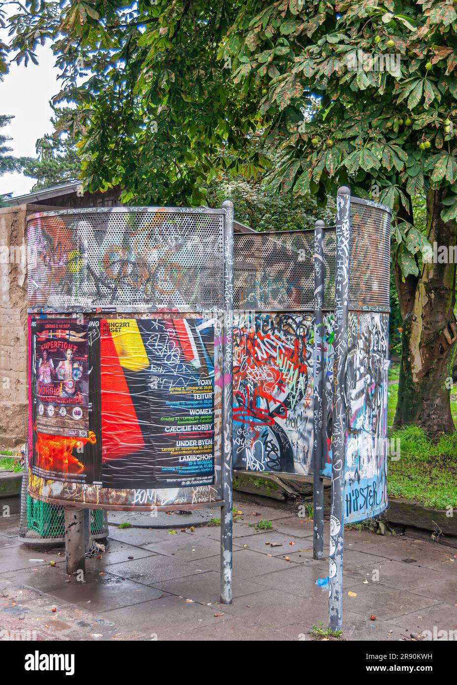 Kopenhagen, Dänemark - 14. September 2010: Christiania freetown. Öffentlicher Urinalraum mit bunten Werbeplakaten unter grünem Laub Stockfoto