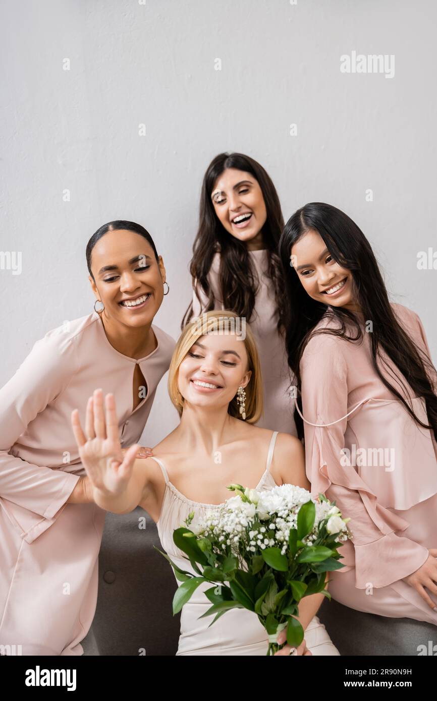 Hochzeitsfotografie, kulturelle Vielfalt, vier Frauen, Braut mit ihren multikulturellen Brautjungfern, die auf Verlobungsring schauen, brünett und blond, positiv Stockfoto