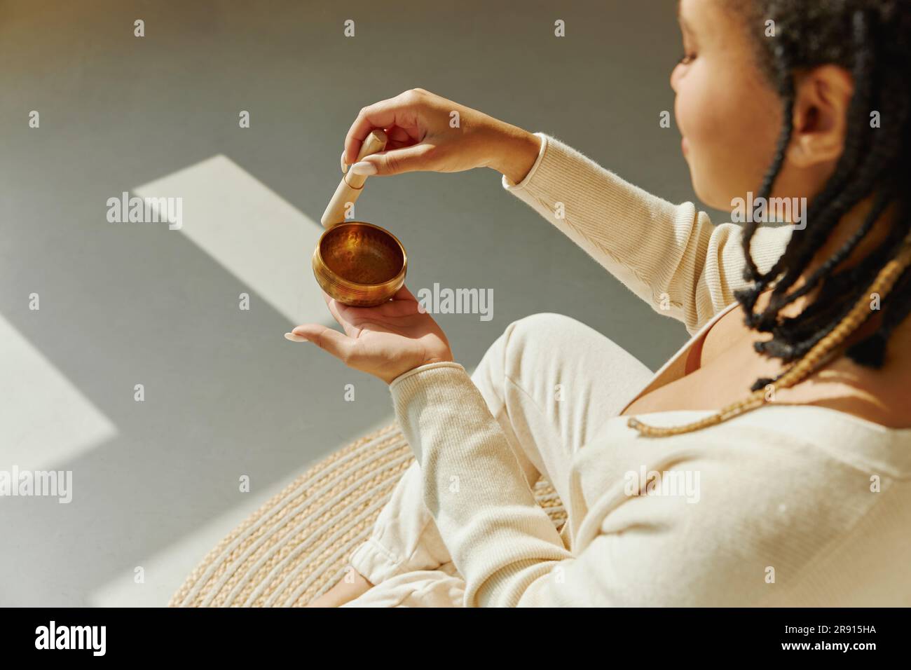 Eine wunderschöne afroamerikanische Frau, die mit einer singenden Schüssel Sound Meditation macht. Stockfoto