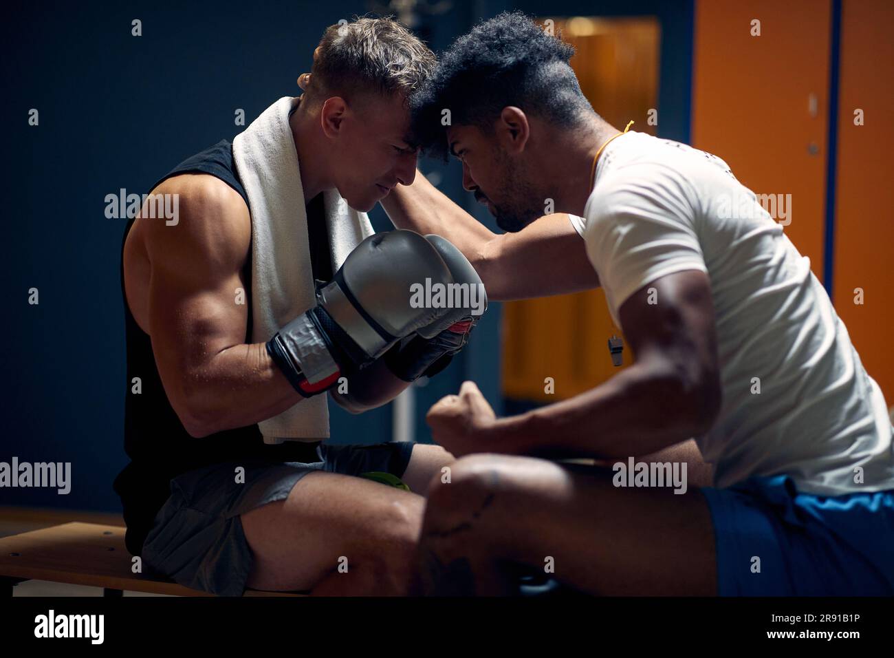 Coach ermutigt jungen Boxspieler, in der Garderobe zu sitzen. Vorbereitung auf das Spiel. Kampfsport, Sport, Lifestyle-Konzept. Stockfoto
