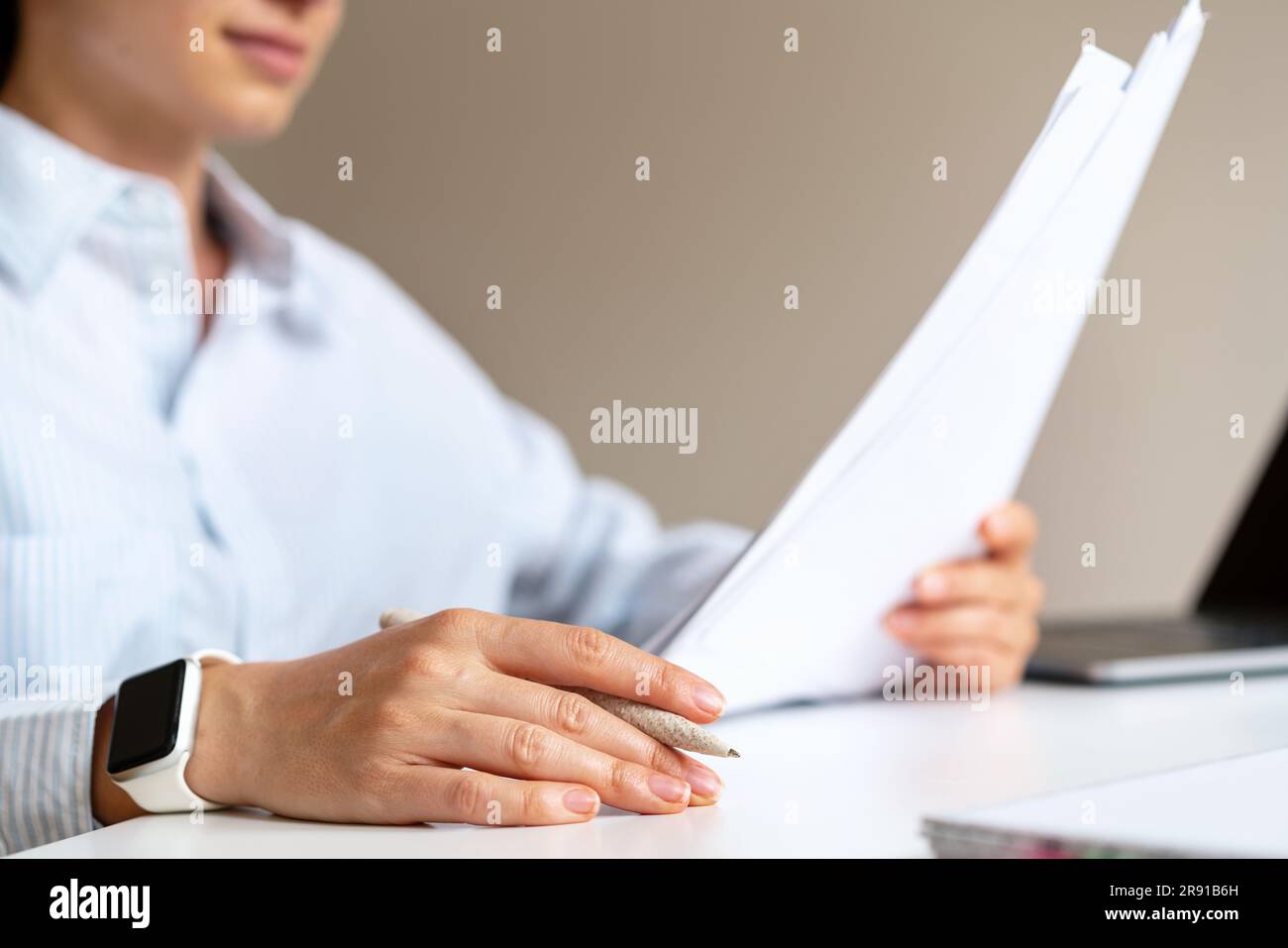 Junge Frau, die am Schreibtisch sitzt und den Darlehensvertrag liest. Stockfoto