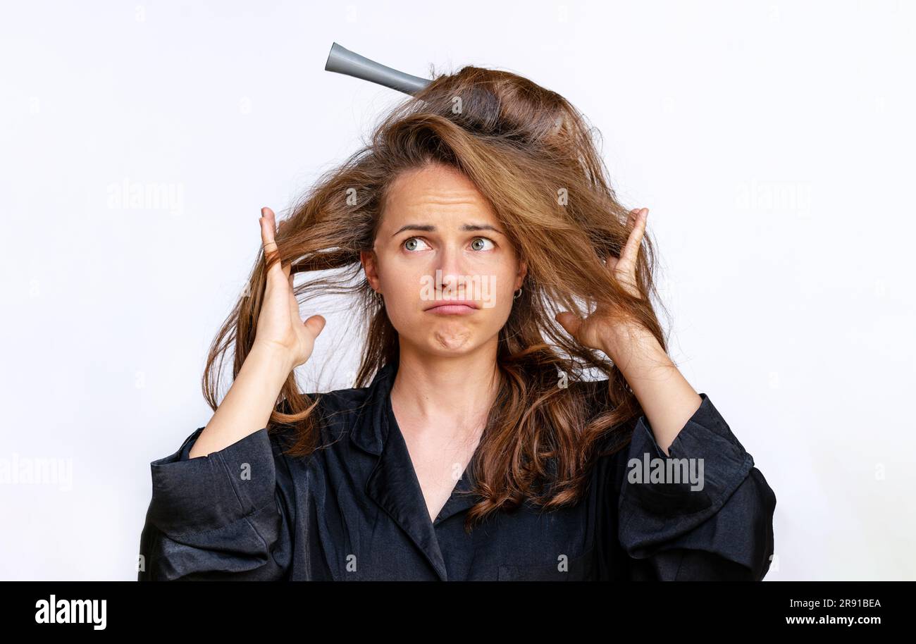 Junge brünette Frau, die erfolglos versucht, ihr Haar mit einem Kamm zu stylen. Stockfoto