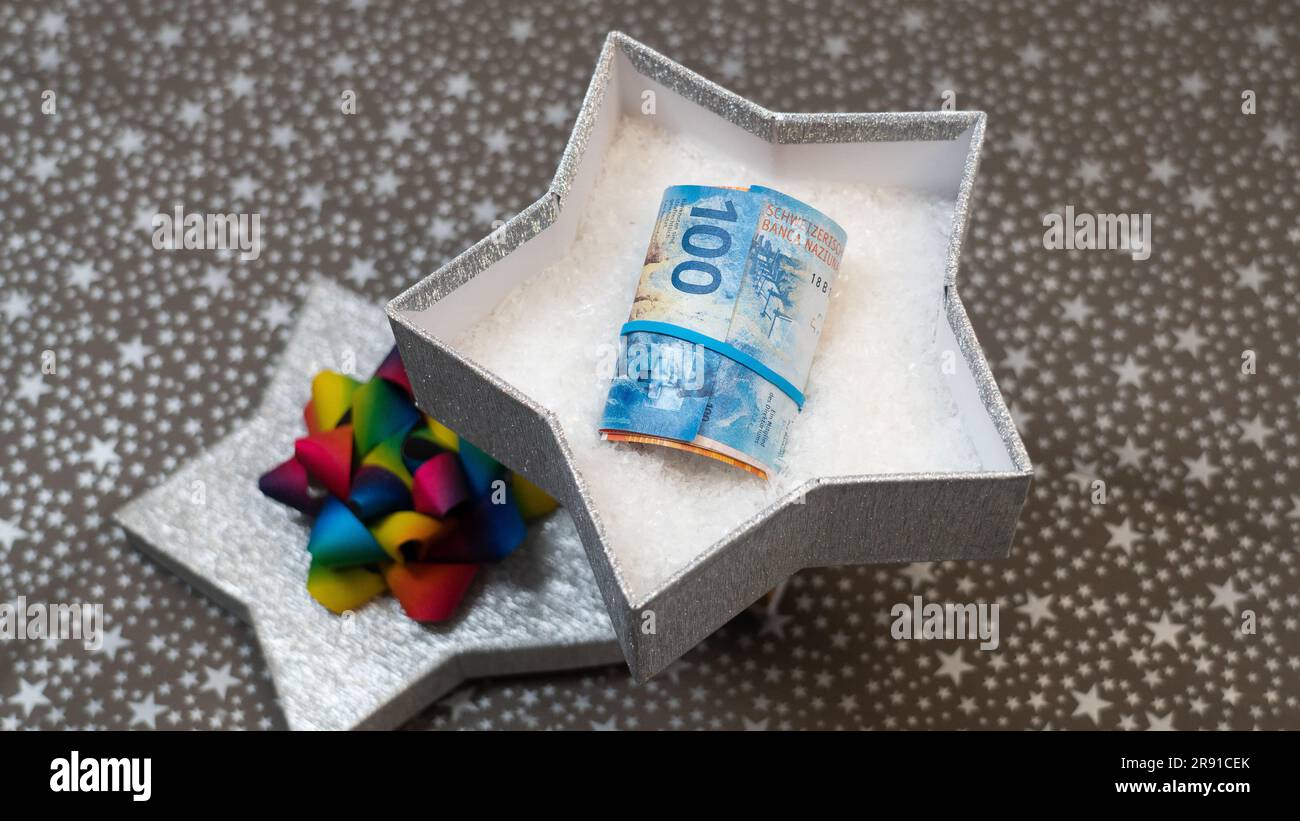 Möglichkeit, Geld zu spenden (schweizer Franken CHF) als Geschenk. Geld als Geschenk zu geben. Ein monetäres Geschenk in einer silbernen, glänzenden Sternenkiste, Sternenmuster, mehrfarbig, Regenbogen Stockfoto