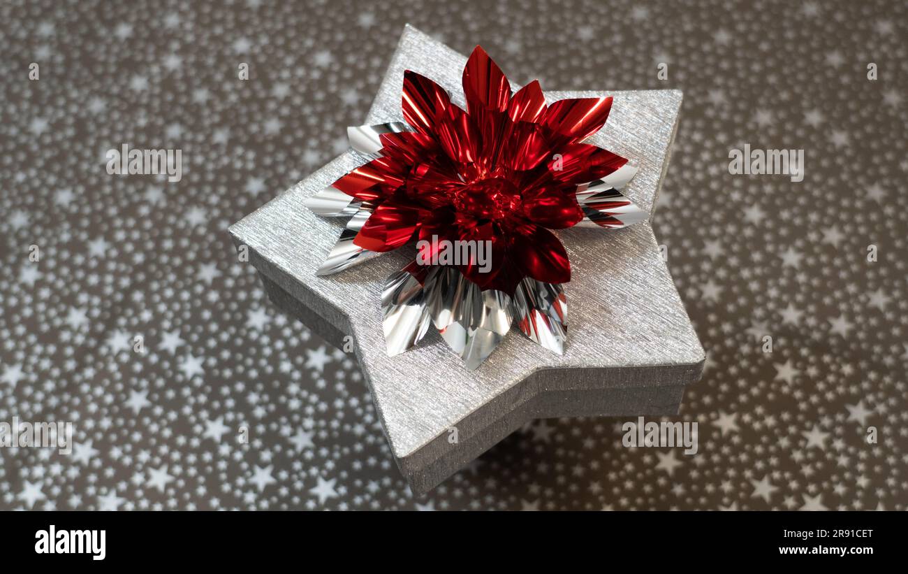 Silberne, glänzende Papierbox ein Stern mit silberroter Schleife (glänzend rote Schleife), perfekt für Weihnachten Stockfoto