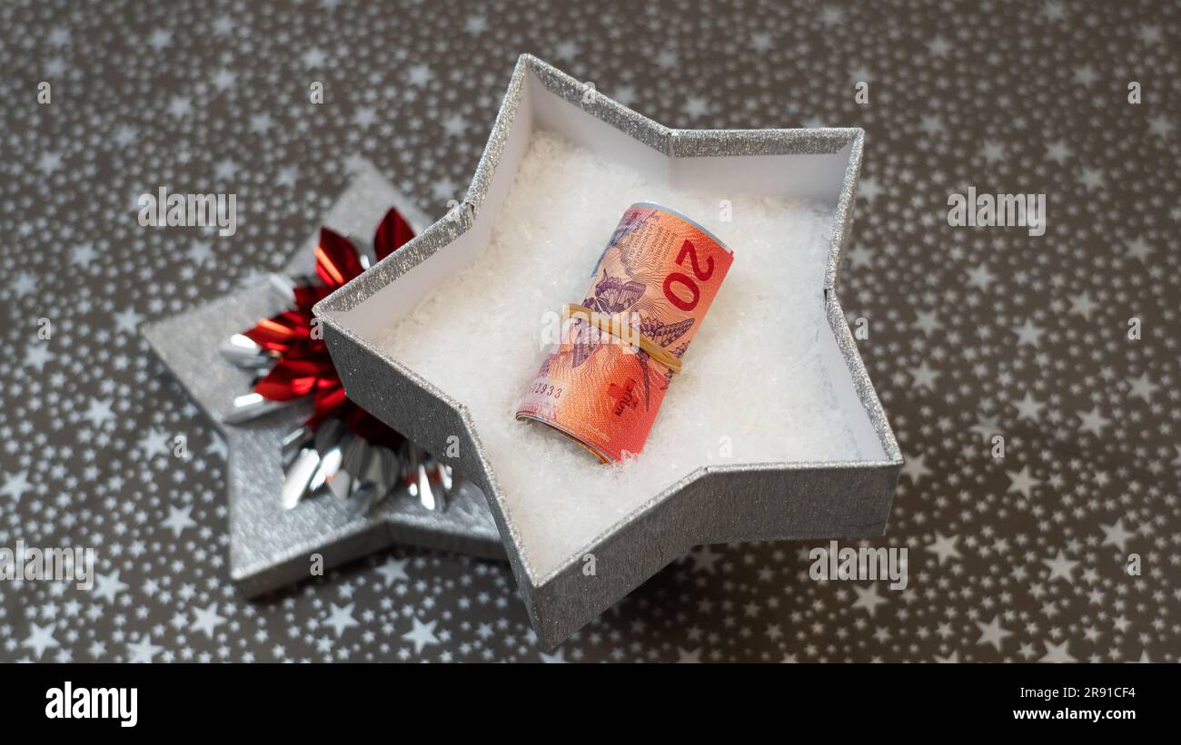 Möglichkeit, Geld zu spenden (schweizer Franken CHF) als Geschenk. Geld als Geschenk zu geben. Ein monetäres Geschenk in einer silbernen, glänzenden Sternenkiste, Sternenmuster, mehrfarbig, Regenbogen Stockfoto