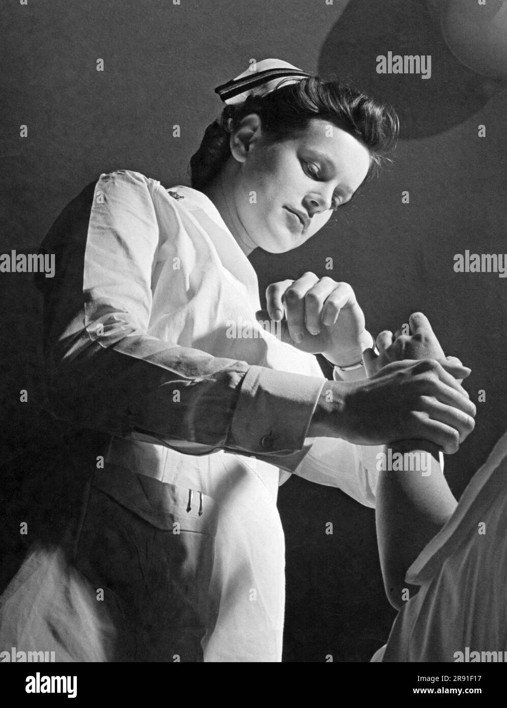 Vereinigte Staaten: Januar 1944 Eine USA Navy-Krankenschwester im Dienst bei den USA Marine Corps Women's Reserve überprüft den Puls eines Patienten. Stockfoto