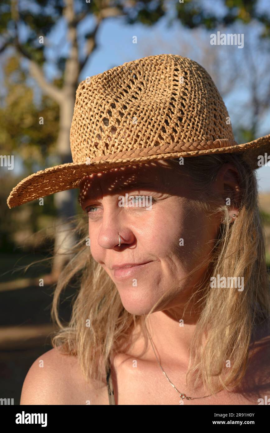 Eine Frau in einem Bikini und einem Strohhut genießt die Hitze im Outback in Australien Stockfoto