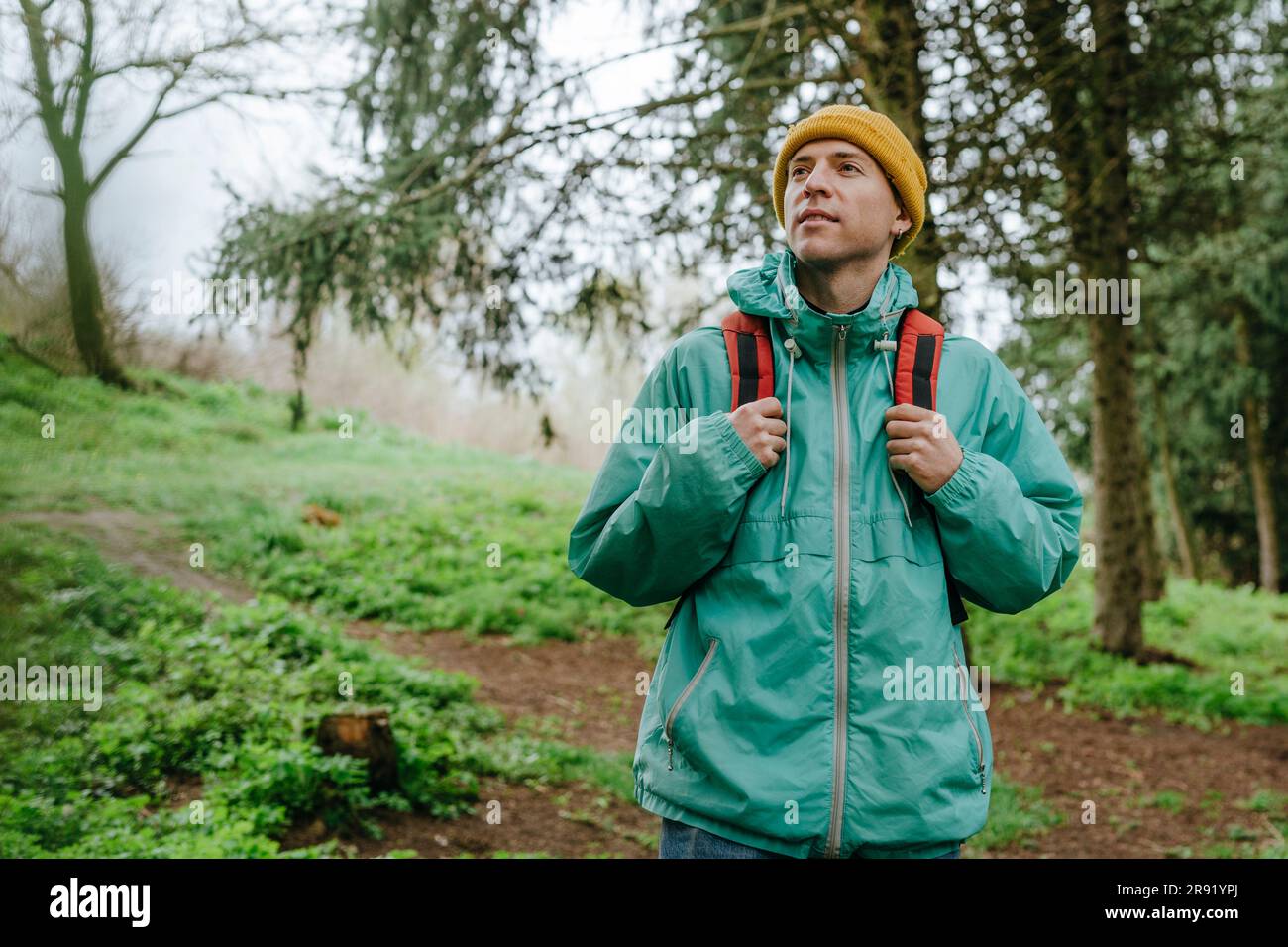 Rucksacktourist mit Regenmantel wandern im Wald Stockfoto