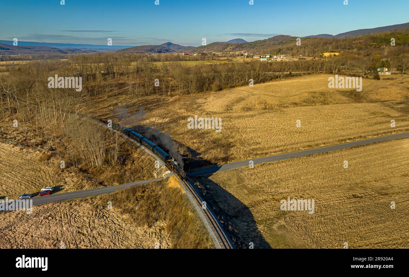 Ein Blick aus der Vogelperspektive auf einen Dampflokomodus, der eine Kurve rundet, Rauch und Dampf an einem sonnigen Wintertag bläst Stockfoto