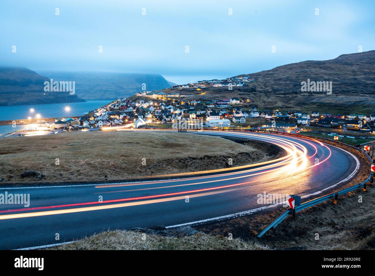 Leichte Wanderwege auf der Straße mit EIDI-Stadt im Hintergrund in der Dämmerung, Färöer-Inseln Stockfoto