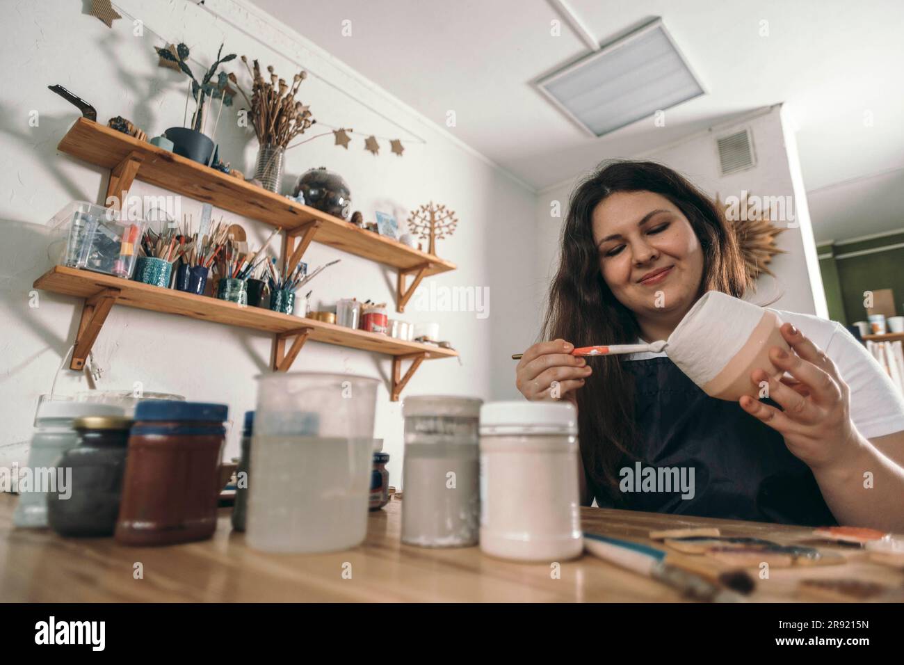Lächelnder Töpfer, der Keramiktopf in der Werkstatt malt Stockfoto
