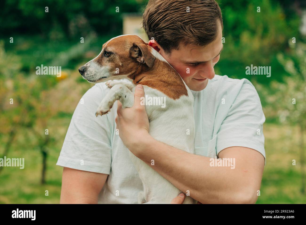 Glücklicher Mann umarmt Jack Russell Terrier Hund im Garten Stockfoto
