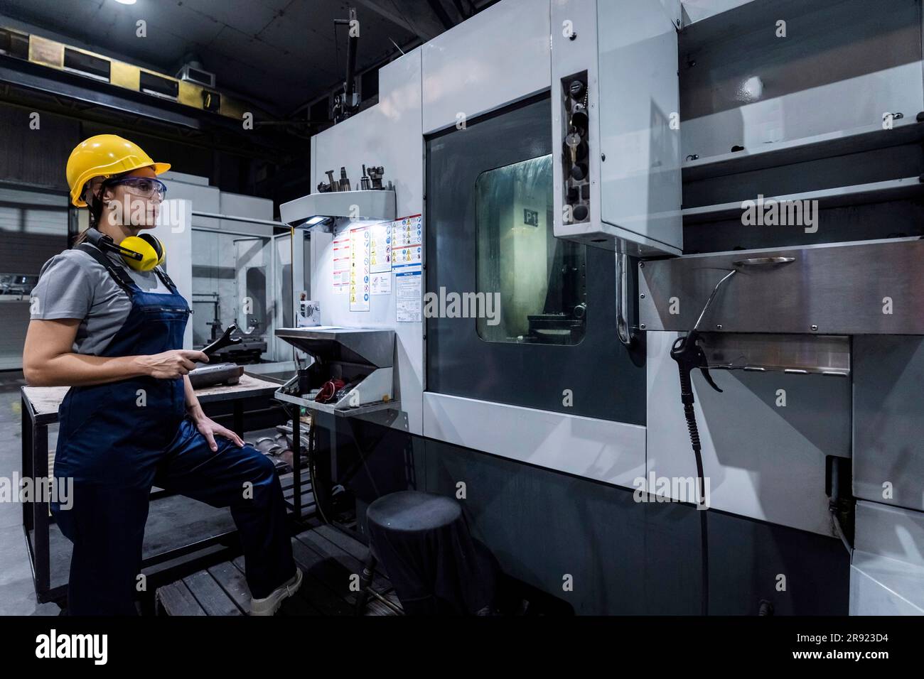 Wartungstechniker hält den Schraubenschlüssel in einer modernen Fabrik an der CNC-Maschine Stockfoto