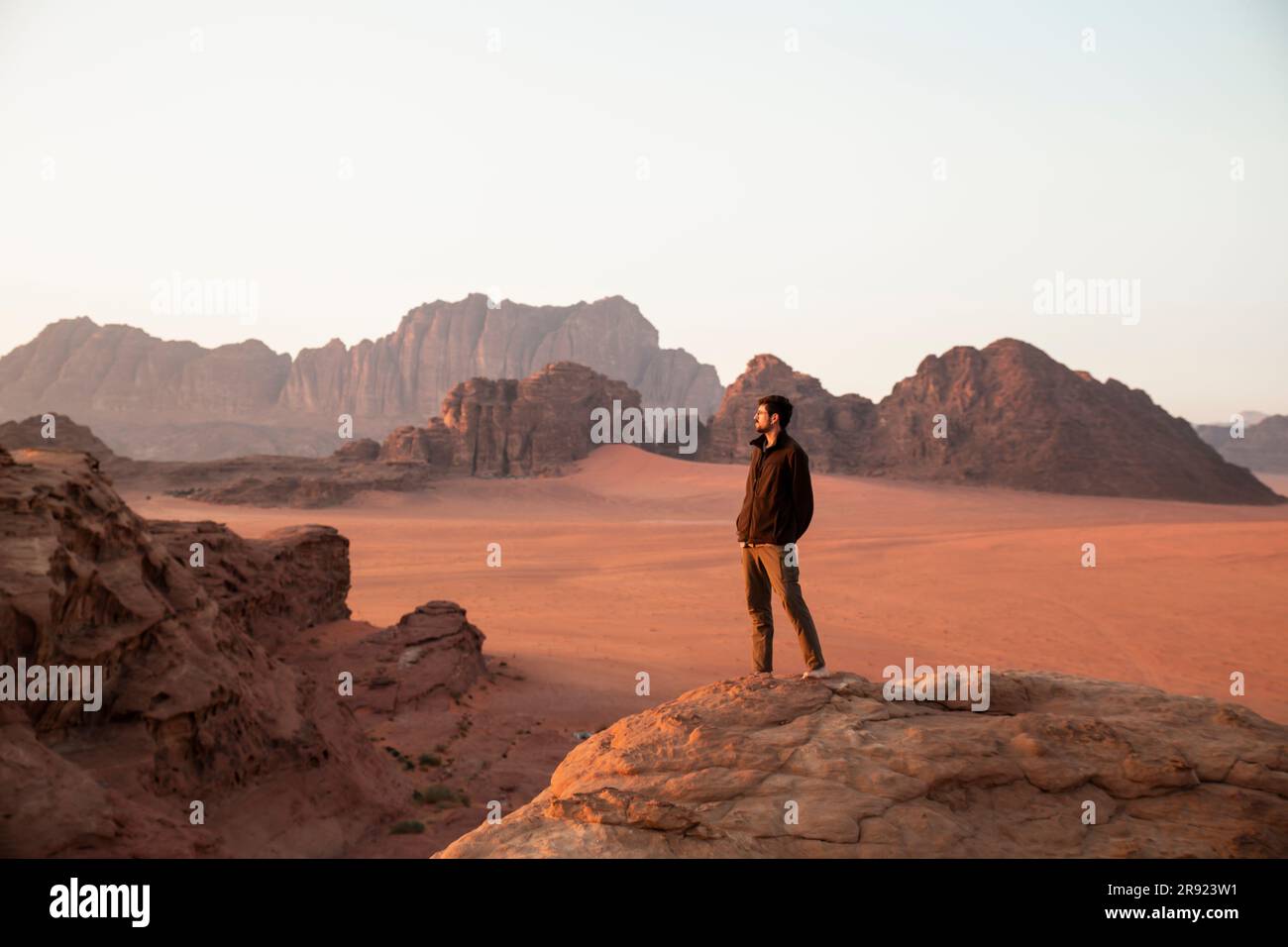 Ein Mann, der bei Sonnenuntergang auf Wüstenfelsen steht Stockfoto