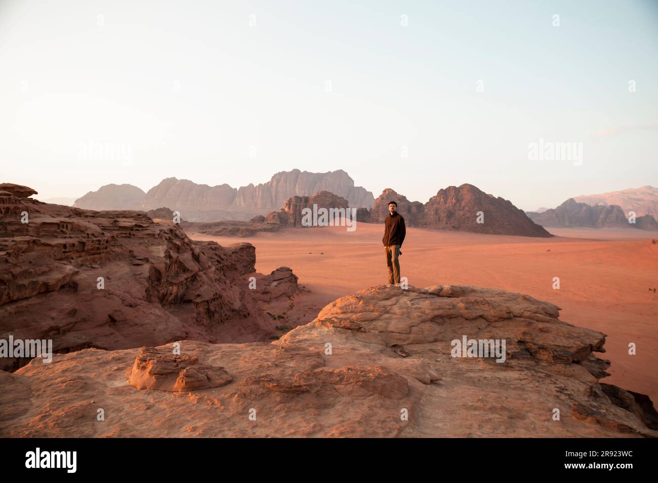 Junger Mann, der bei Sonnenuntergang auf Wüstenfelsen steht Stockfoto