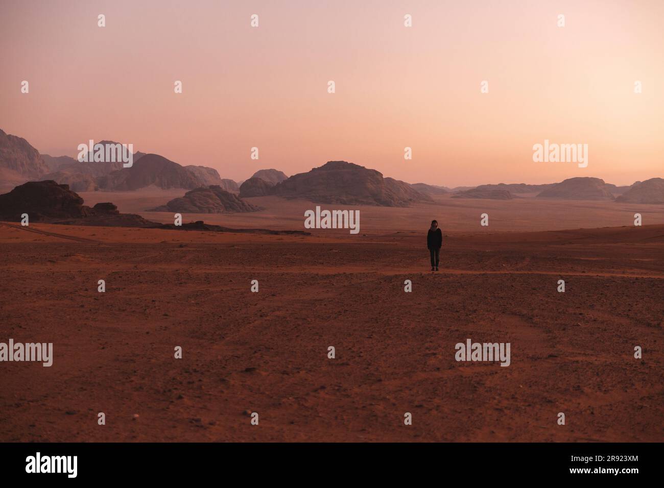 Junge Frau, die bei Sonnenuntergang in der Wüste spaziert Stockfoto