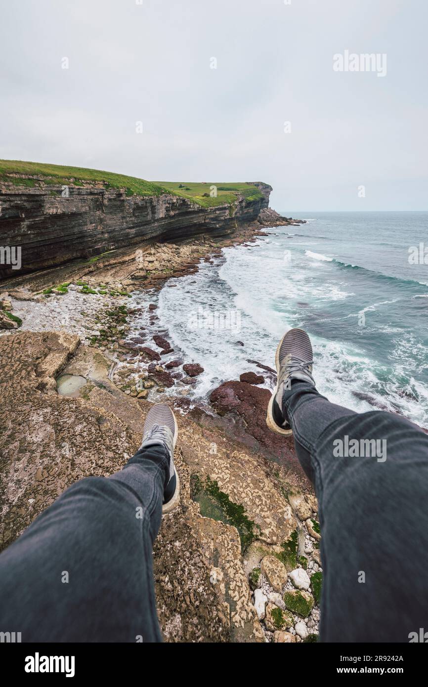 Mann sitzt auf einem Felsen mit Strand im Hintergrund Stockfoto