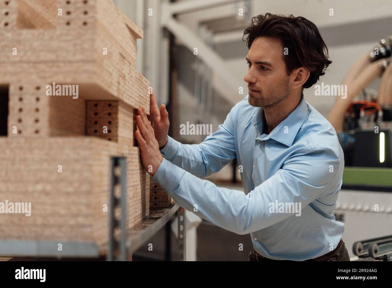 Geschäftsmann, der in der Industrie Holz auf Regalen stapelt Stockfoto
