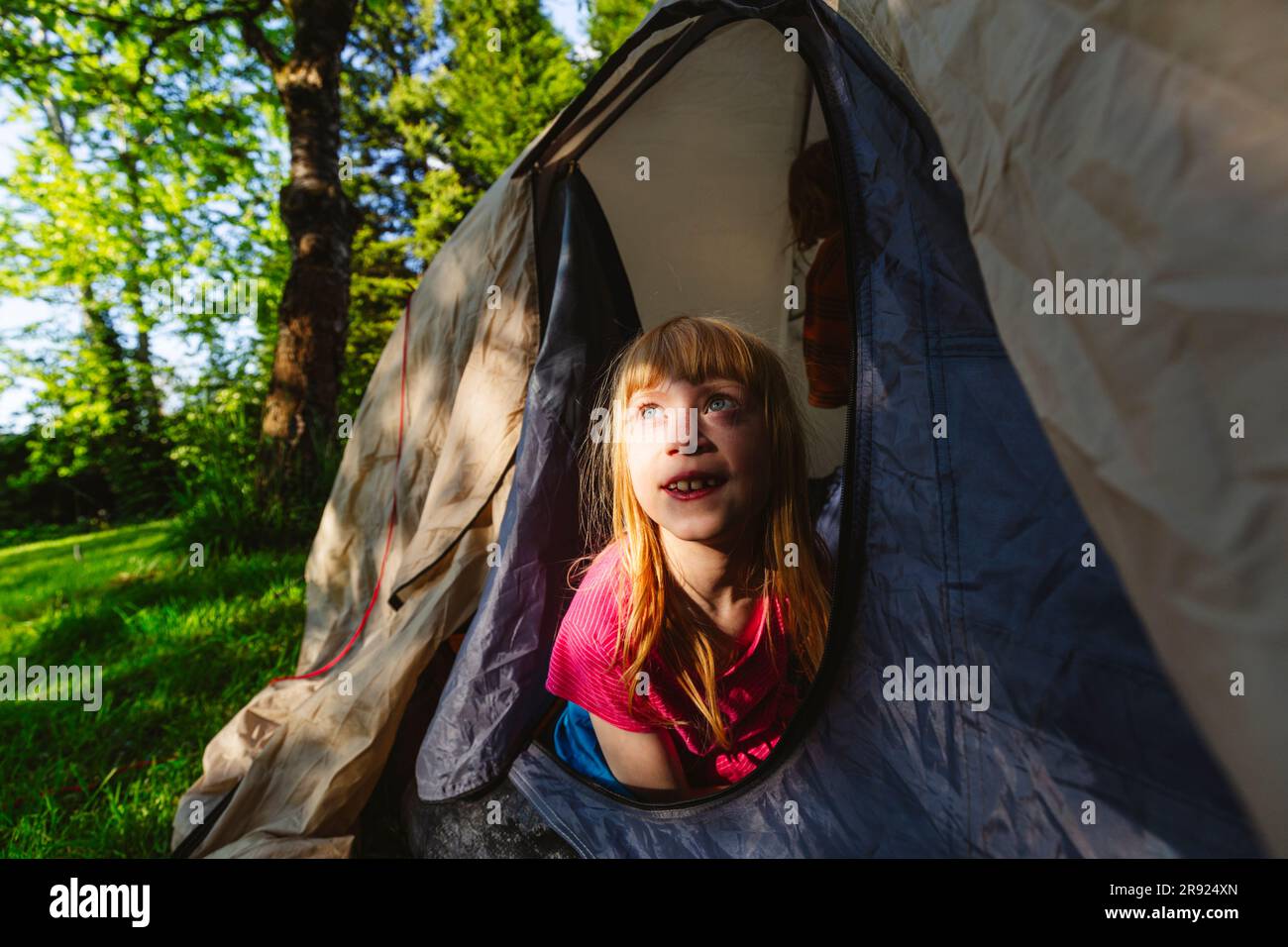 Rücksichtsvolles, erdbeerblondes Mädchen, das im Zelt sitzt Stockfoto