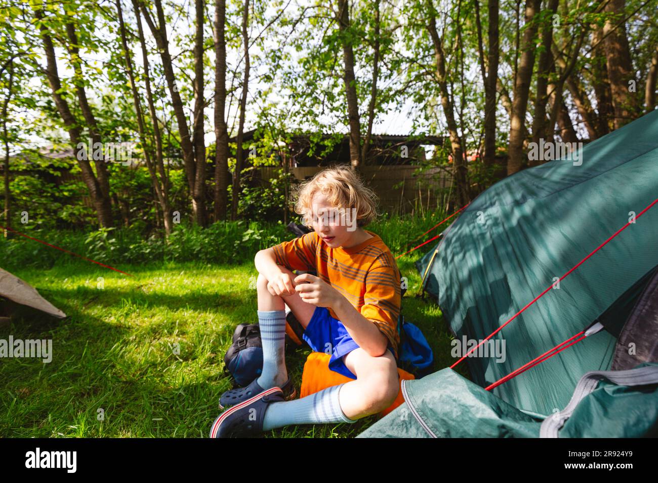 Der Junge sitzt am Zelt im Park Stockfoto