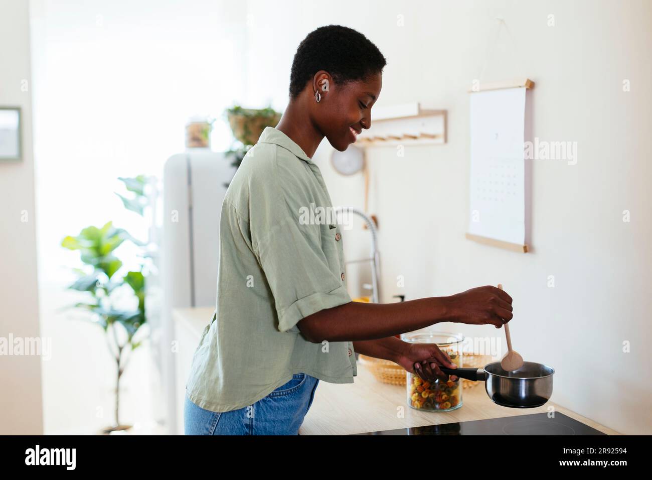 Glückliche junge Frau, die zu Hause Essen kocht Stockfoto