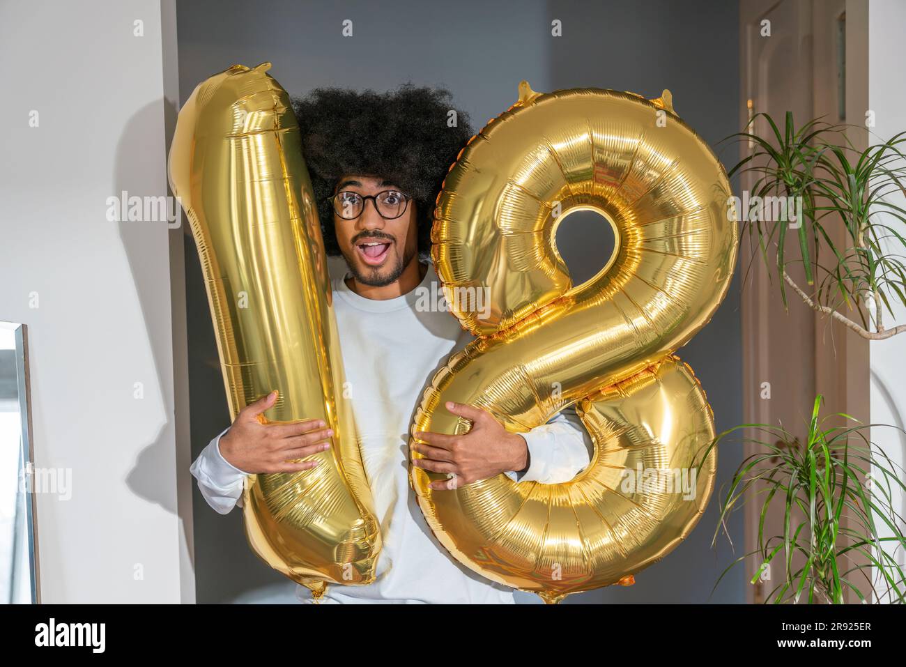 Ein Überraschungsmann, der zu Hause einen Ballon mit der Nummer 18 hält Stockfoto
