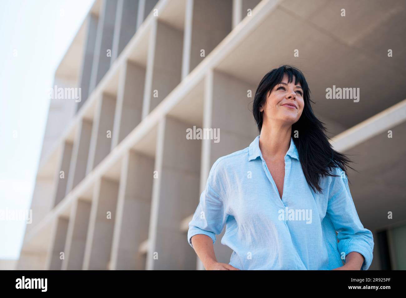 Geschäftsfrau mit blauem Hemd, die vor dem Gebäude steht Stockfoto