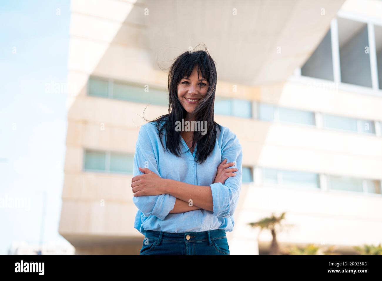 Lächelnde Geschäftsfrau mit langen Haaren vor dem Gebäude Stockfoto