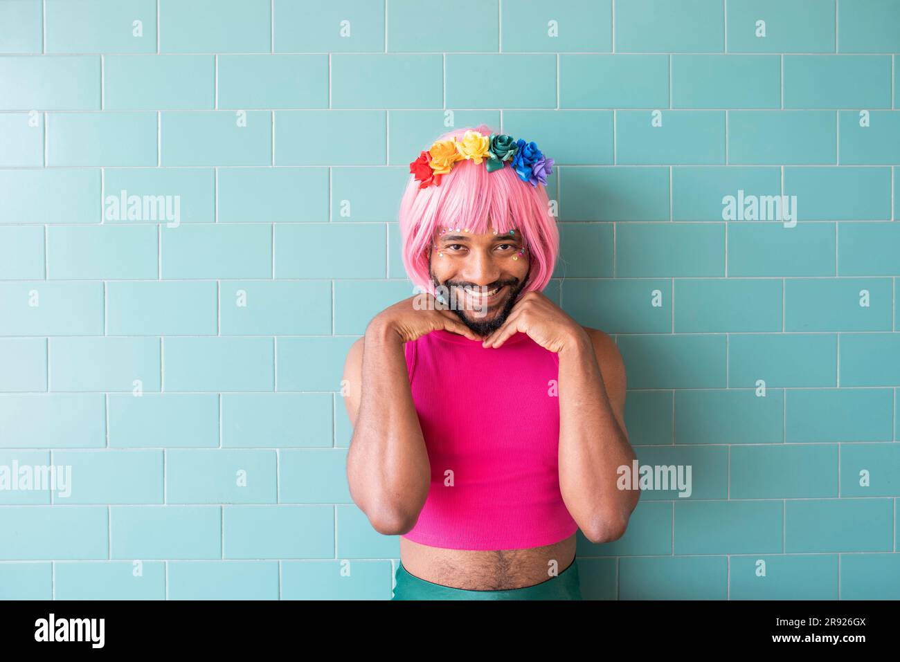 Ein lächelnder Mann mit rosa Perücken steht vor der Wand Stockfoto