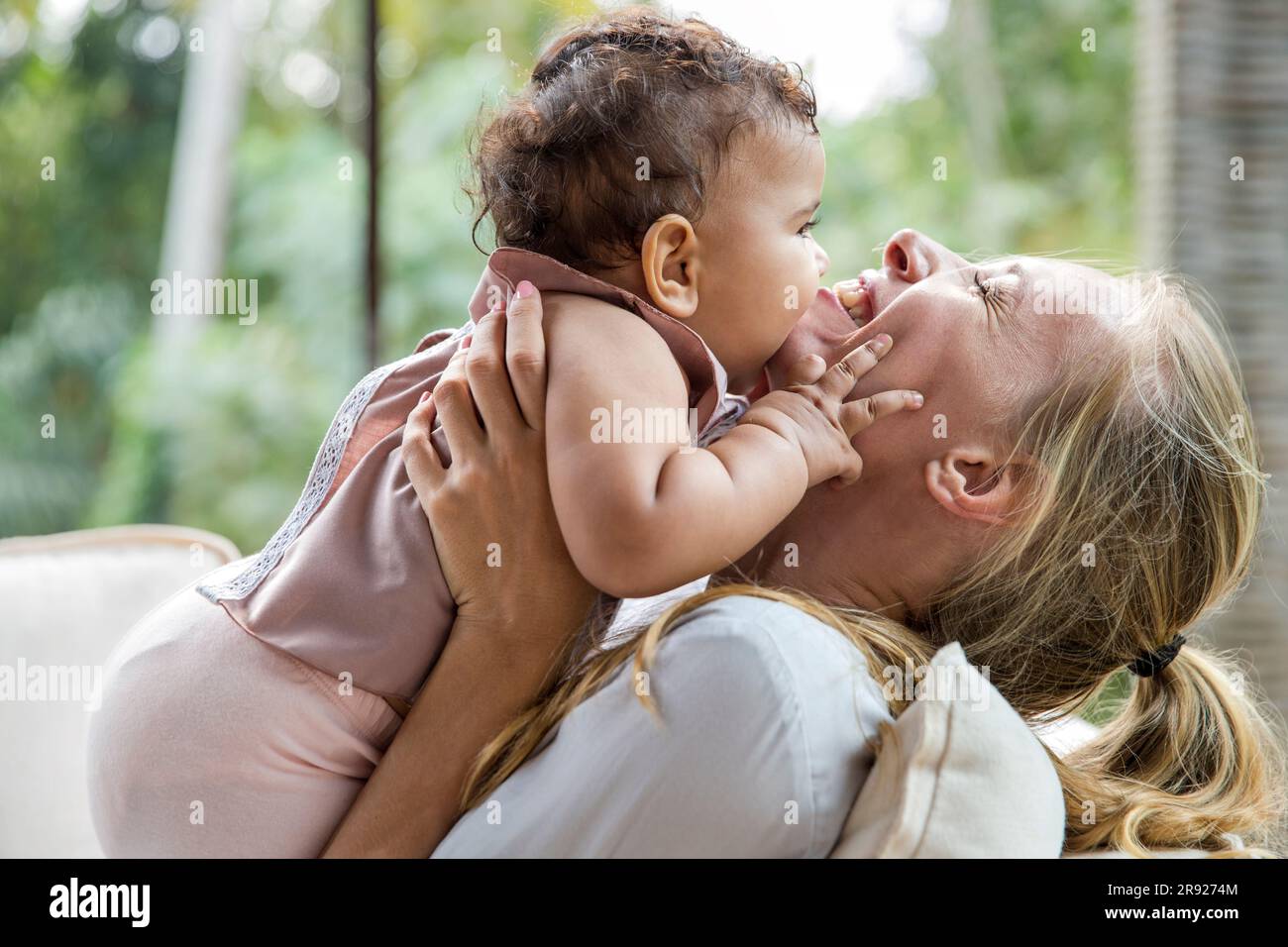 Fröhliche Mutter mit einer kleinen Tochter, die sich zu Hause umarmt Stockfoto