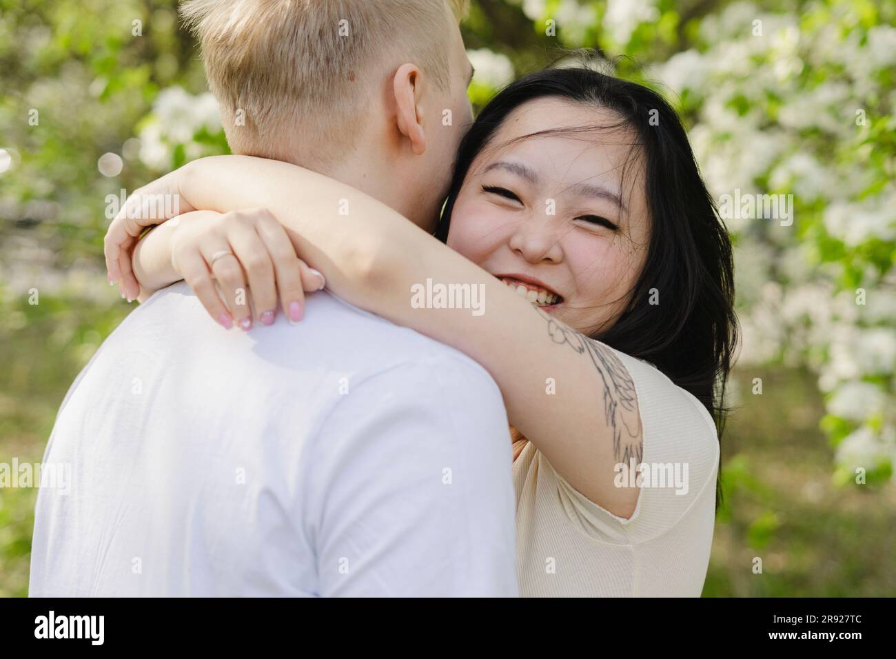 Lächelnde junge Frau, die den Mann im Park umarmt Stockfoto