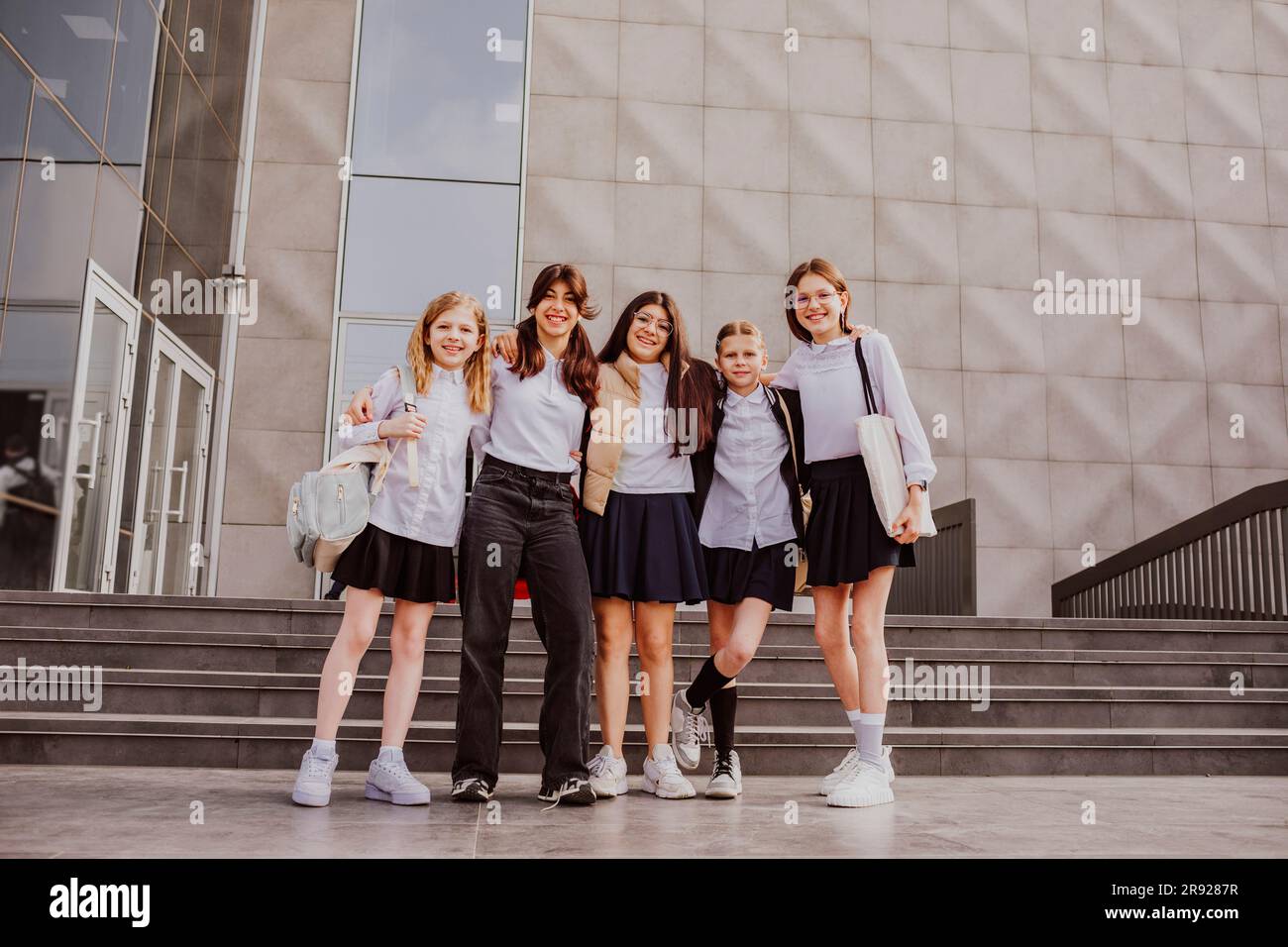 Schulmädchen in Uniformen stehen vor dem Schulgebäude Stockfoto