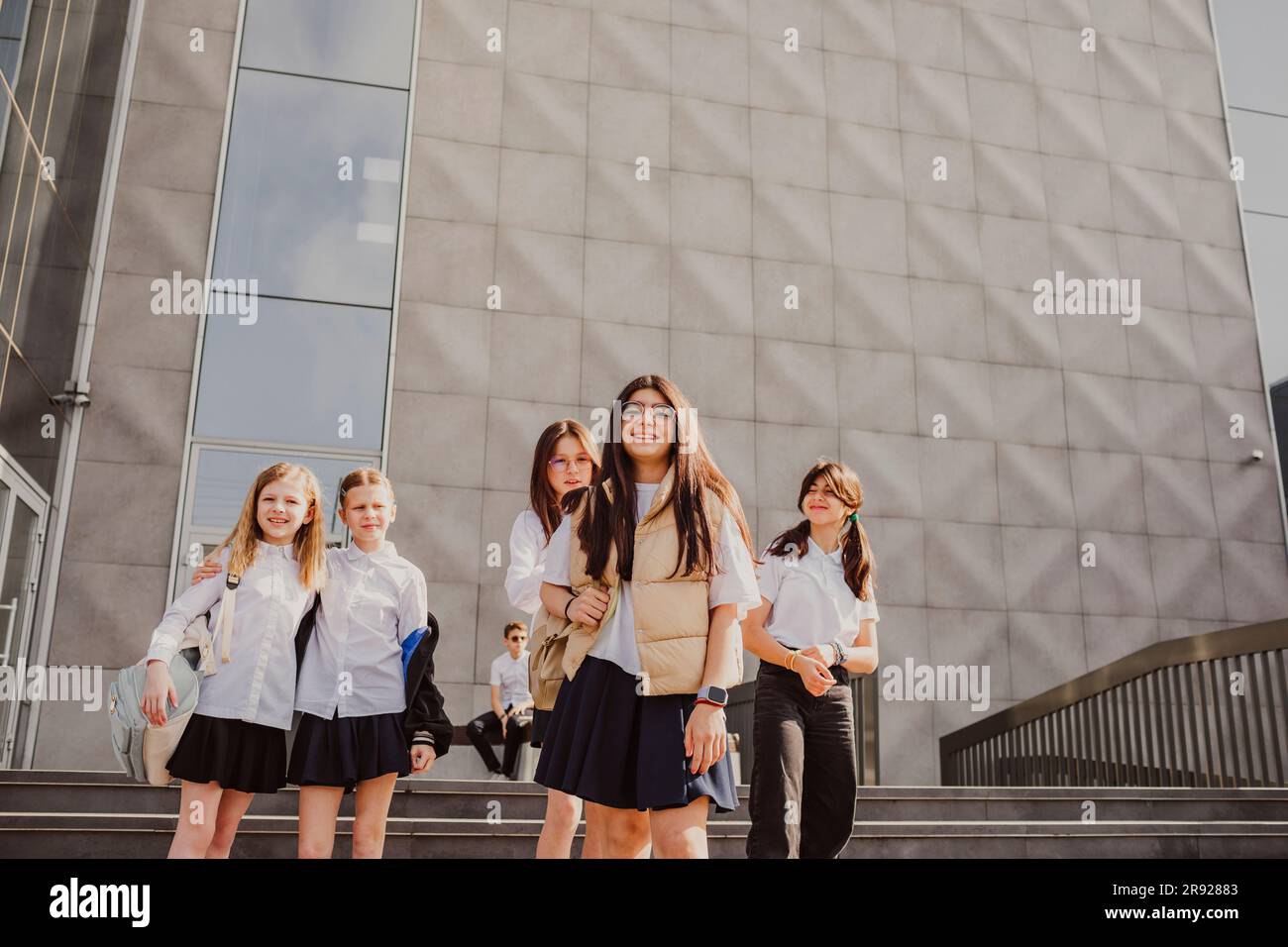 Lächelndes Schulmädchen, das mit Freunden vor dem Gebäude steht Stockfoto