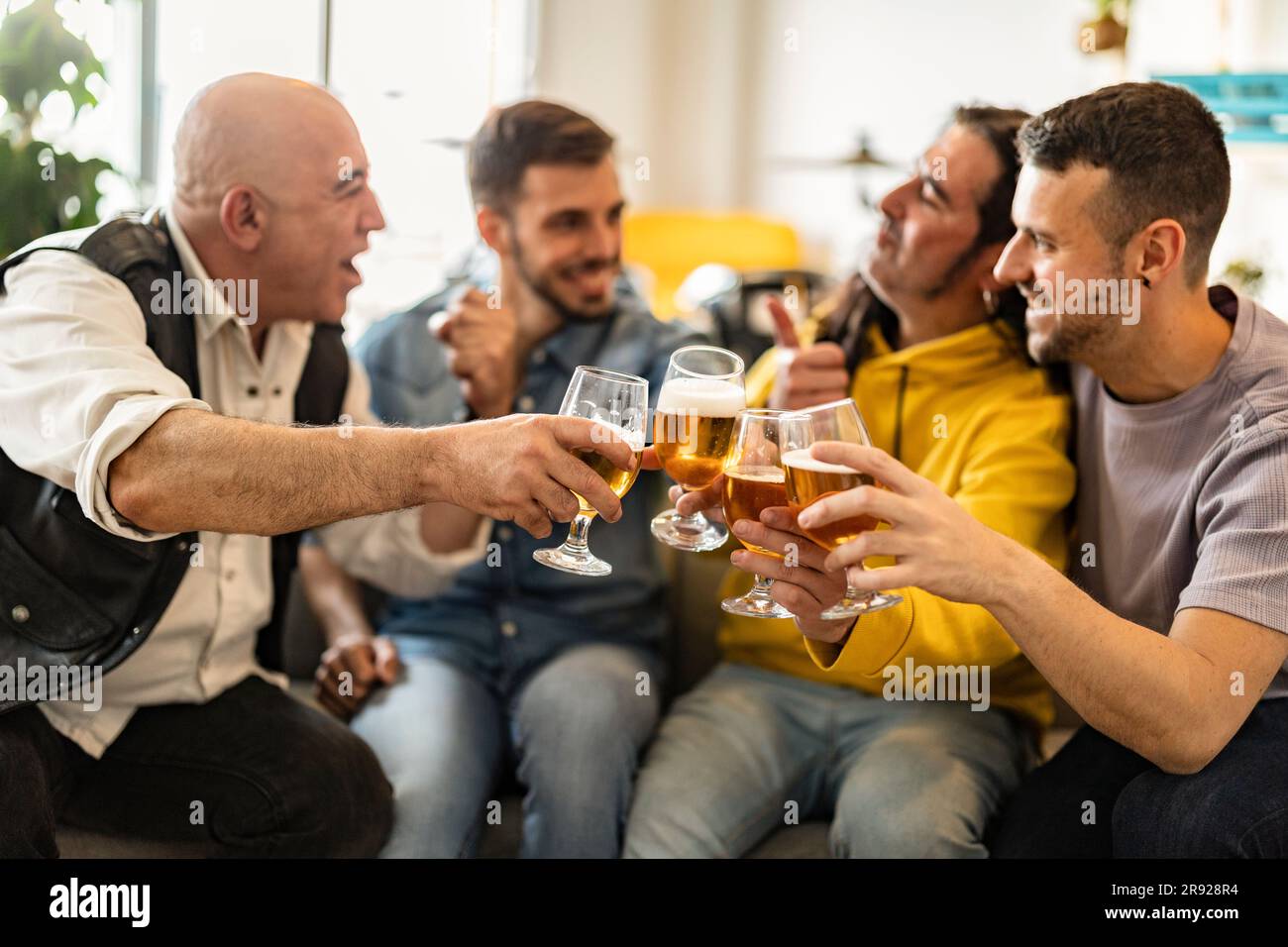 Glückliche Freunde, die zu Hause Bier toasten Stockfoto