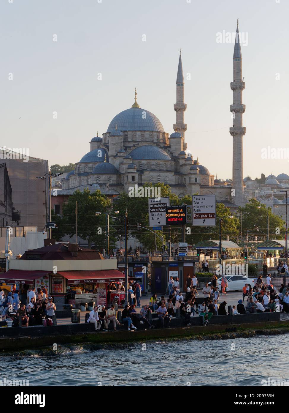 Am Abend sitzen und entspannen sich die Leute am Goldenen Horn in Eminonu mit der Yeni Cami Moschee hinter der Insel, Istanbul, Türkei. Stockfoto