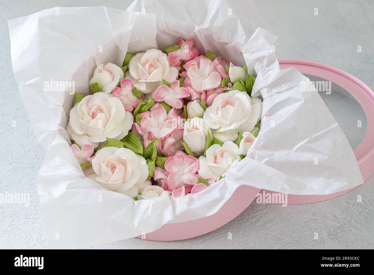 Zephyr-Blumenstrauß in einer Geschenkbox auf hellem Hintergrund. Stockfoto