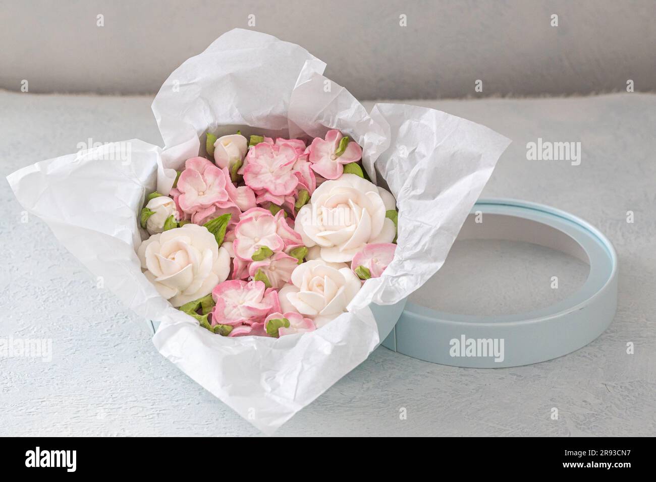 Zephyr-Blumenstrauß in einer Geschenkbox auf hellem Hintergrund. Stockfoto