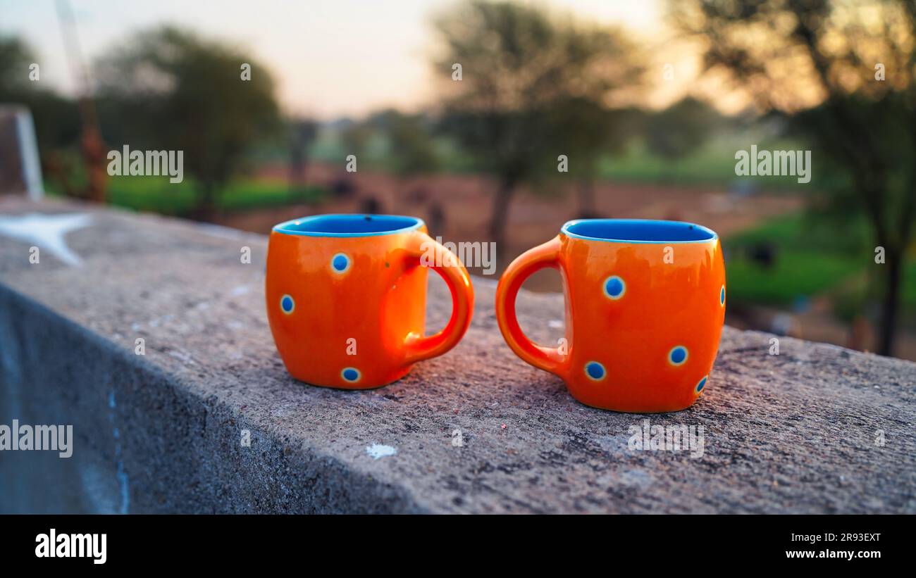 Zwei leere orangefarbene Keramikkaffee- oder -Teetassen auf dem Dach mit Naturhintergrund. Stockfoto