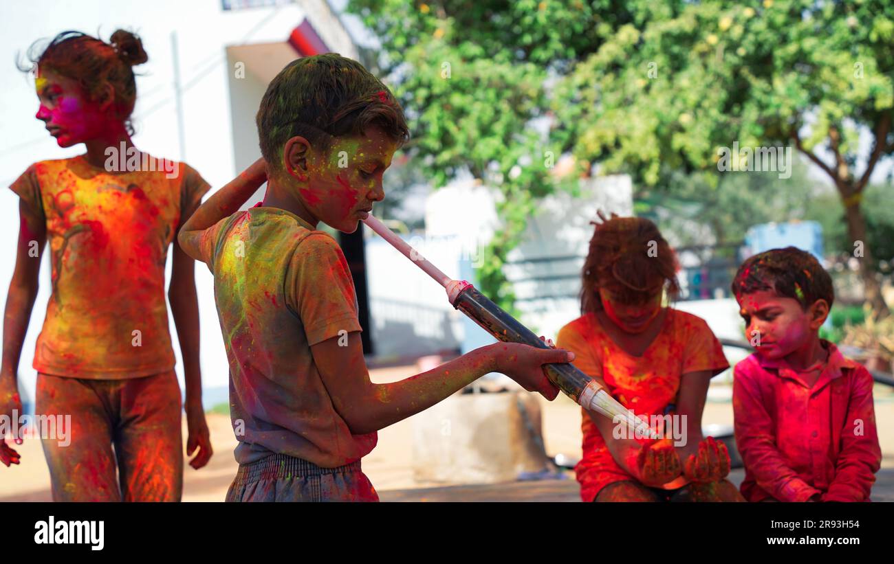 Indische Kinder, die mit Farben spielen, oder asiatische Kinder, die holi mit Pichkari feiern. festival der Farben Stockfoto