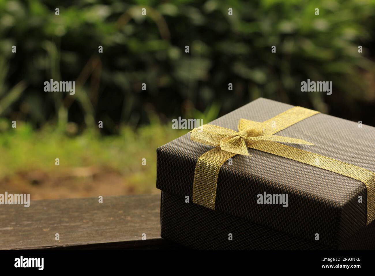 Verschiedene Geschenkschachteln mit Sonnenlicht auf dem Rasen des Parks an einem sonnigen Sommertag:Schachtel für Geschenk mit goldenem Band auf dem Holztisch Stockfoto