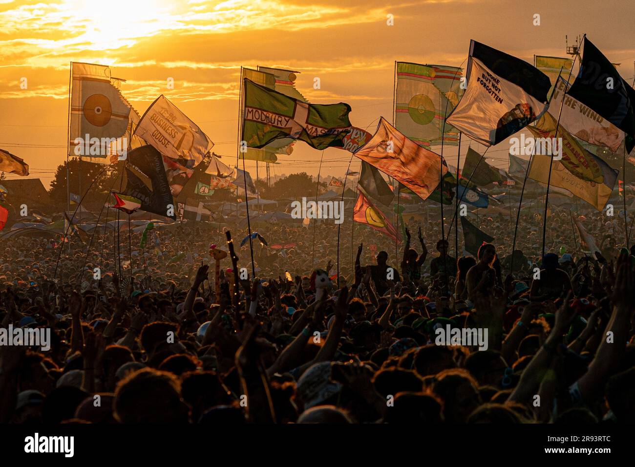 Die Flaggen winken und die Menschenmassen singen mit und tanzen auf den Schultern, während Fred auf der anderen Bühne beim Sonnenuntergang über dem Glastonbury Festival auf der Worthy Farm in Somerset zusieht. Foto: Freitag, 23. Juni 2023. Stockfoto