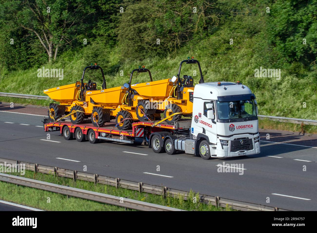 LOGISTICA Brit European Group 2023 Renault Truck T mit Stufenrahmen-Anhänger, der neue JCB 6T-2, 6 Tonnen Site Dumper-Lkw befördert; Fahrt auf der Autobahn M6 im Großraum Manchester, Großbritannien Stockfoto