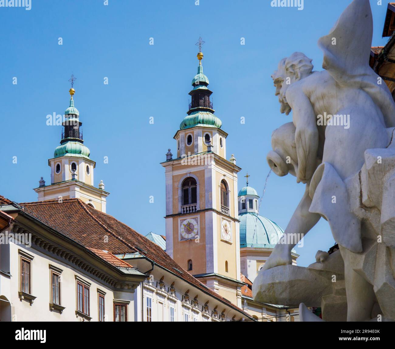 Ljubljana, Slowenien. Türme und Kuppeln der Kathedrale von Ljubljana vom Marktplatz aus zu sehen. Im Vorstehenden werden auch die Figuren auf dem Robba-Brunnen genannt Stockfoto