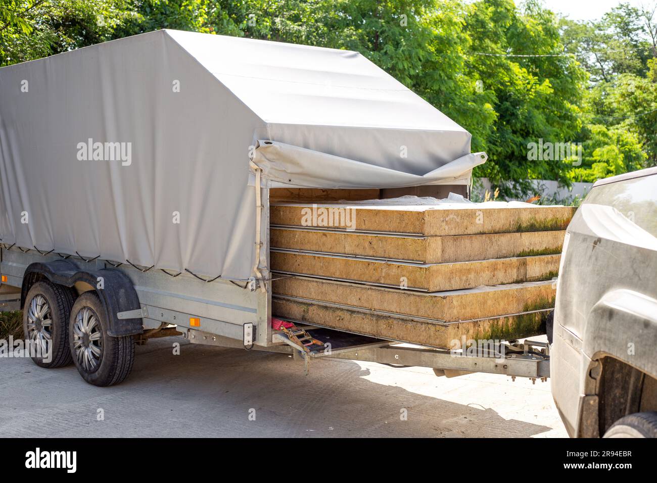 Transport von Fassadenisolierten Paneelen in einem Pkw-Anhänger. Beladener Anhänger. Stockfoto