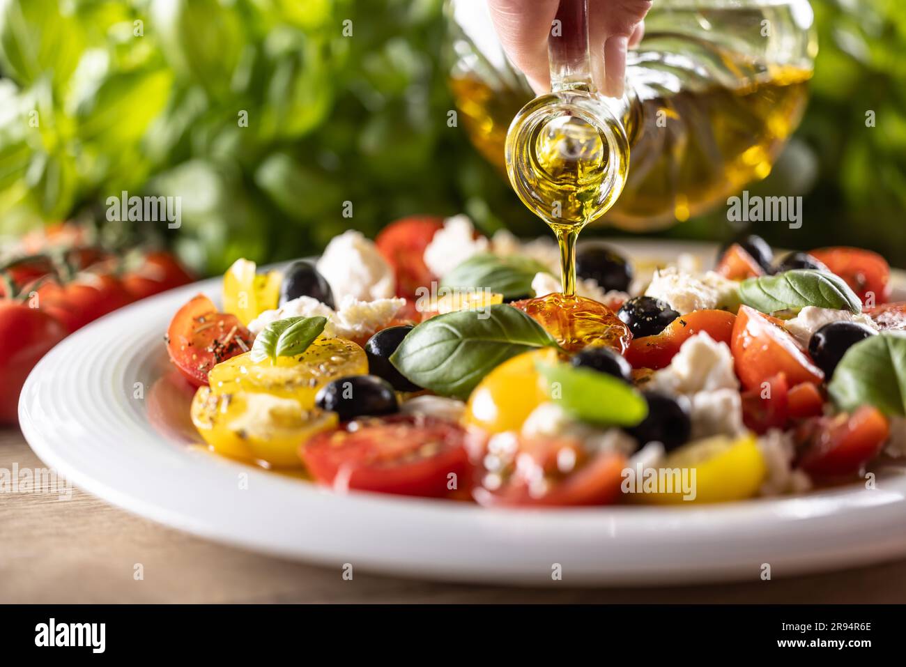 Der Caprese-Salat wird mit Olivenöl geölt. Stockfoto