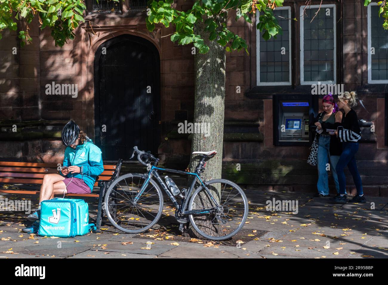 Männlicher Deliveroo-Fahrer, der sein Handy in Chester City Centre, Chester, Großbritannien, überprüft. Stockfoto
