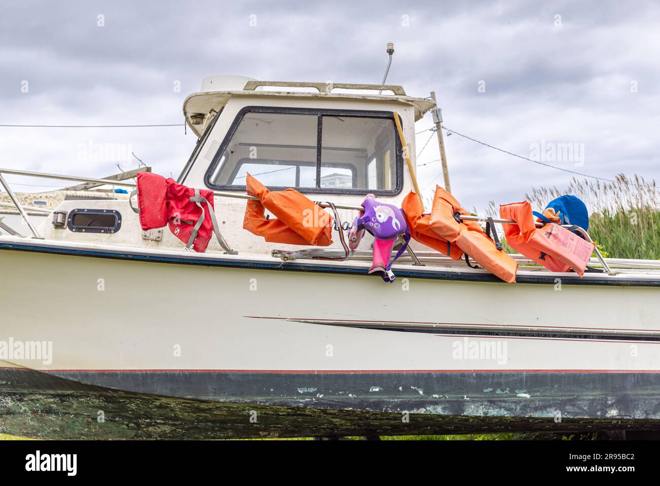 Ein Abschnitt eines Boots aus dem Wasser auf Blöcken mit orangefarbenen Rettungsschwimmern auf der Schiene Stockfoto
