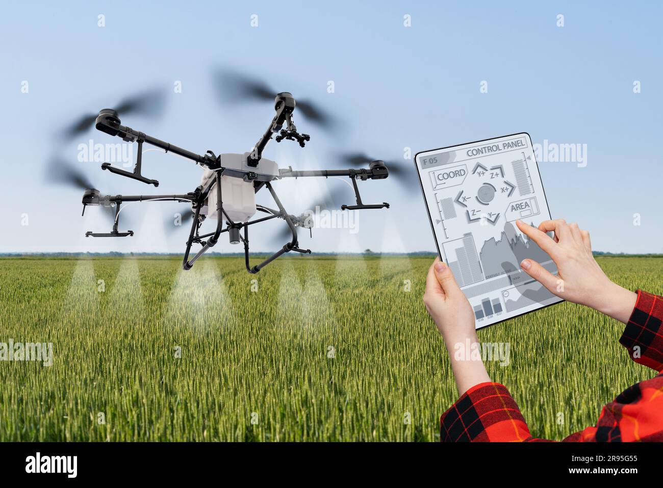 Der Landwirt steuert das Drohnenspray mit einem Tablet. Intelligente Landwirtschaft und Präzisionslandwirtschaft. Stockfoto
